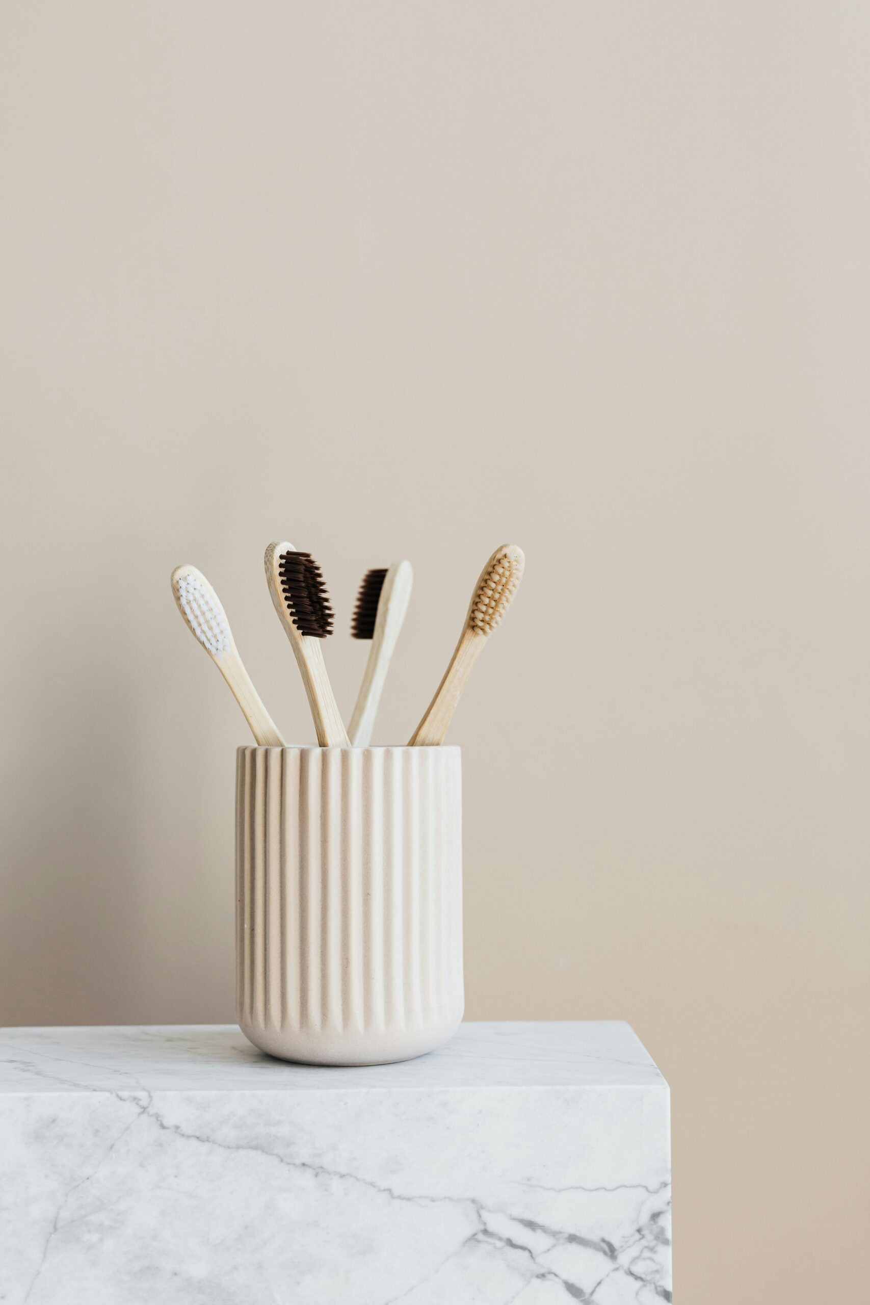 Minimalist bamboo toothbrushes in a ceramic holder for eco-friendly oral care.